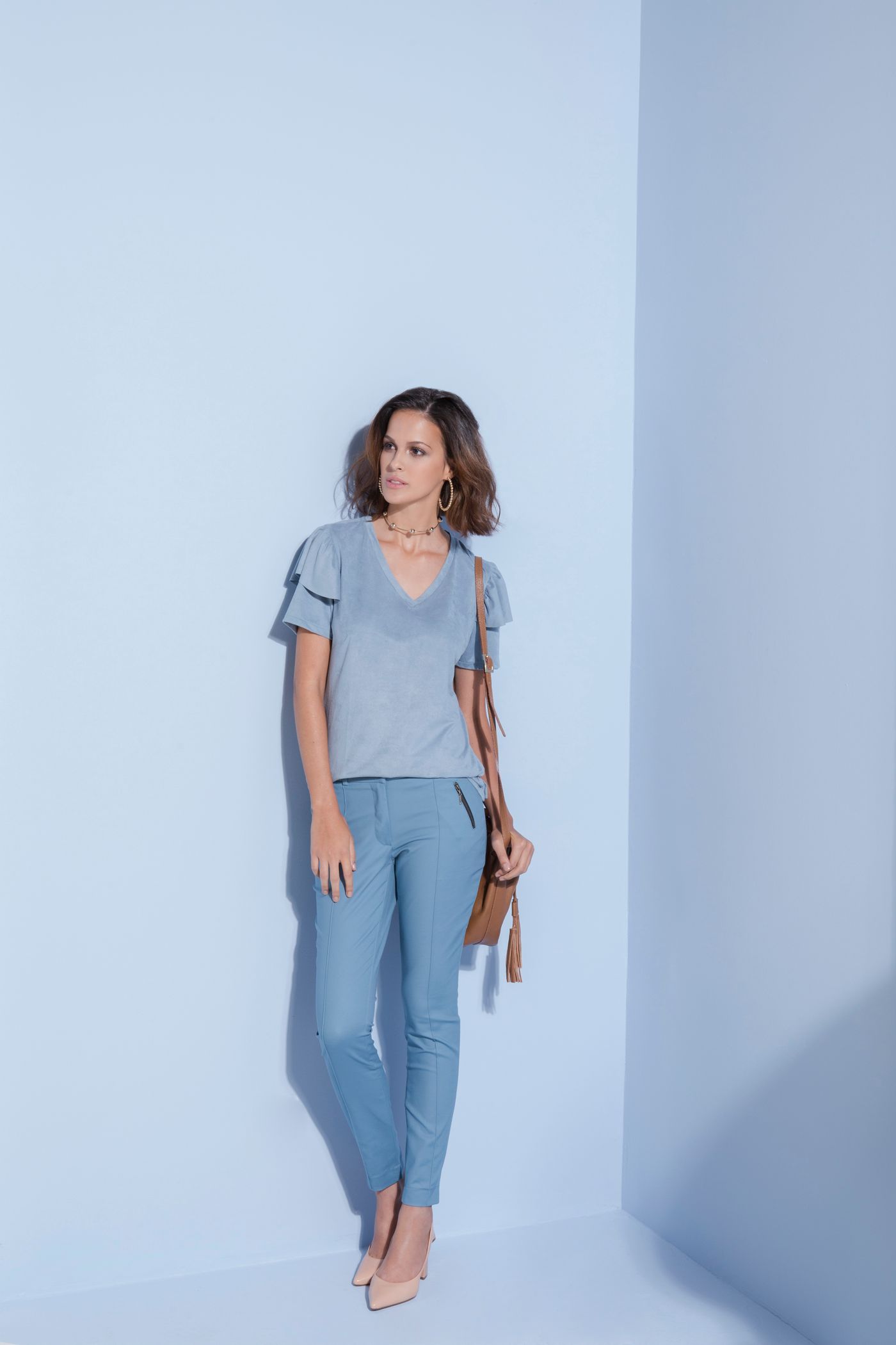 Woman wearing a light blue top and slightly darker blue trousers.