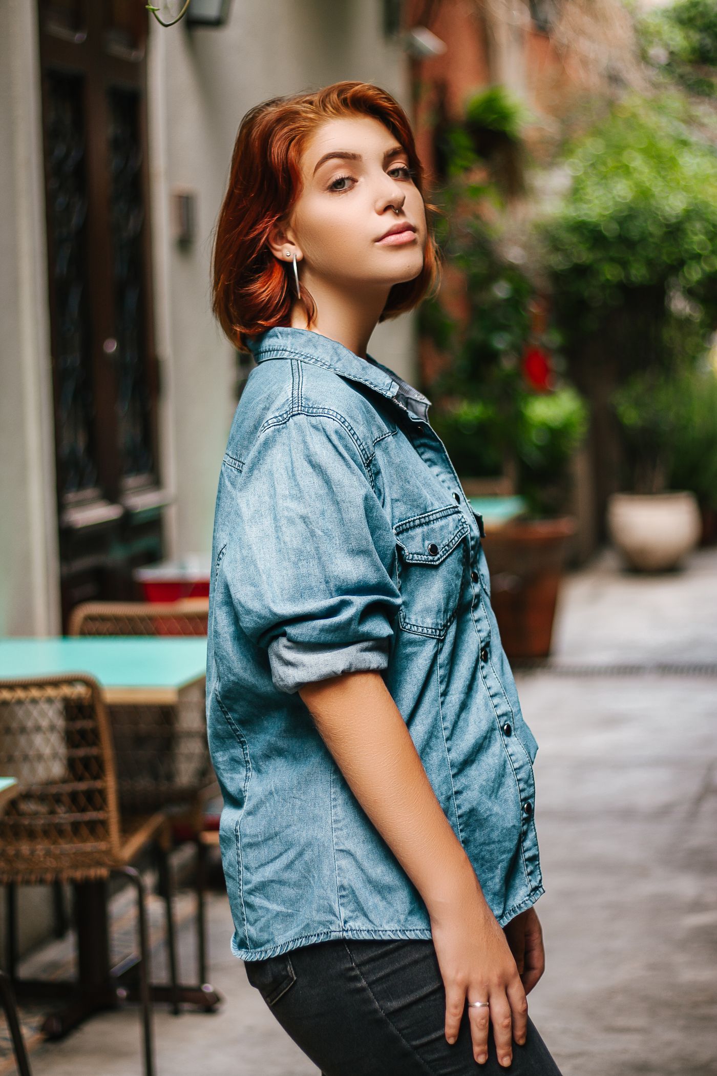 Woman wearing a blue denim shirt with dark non-denim trousers.