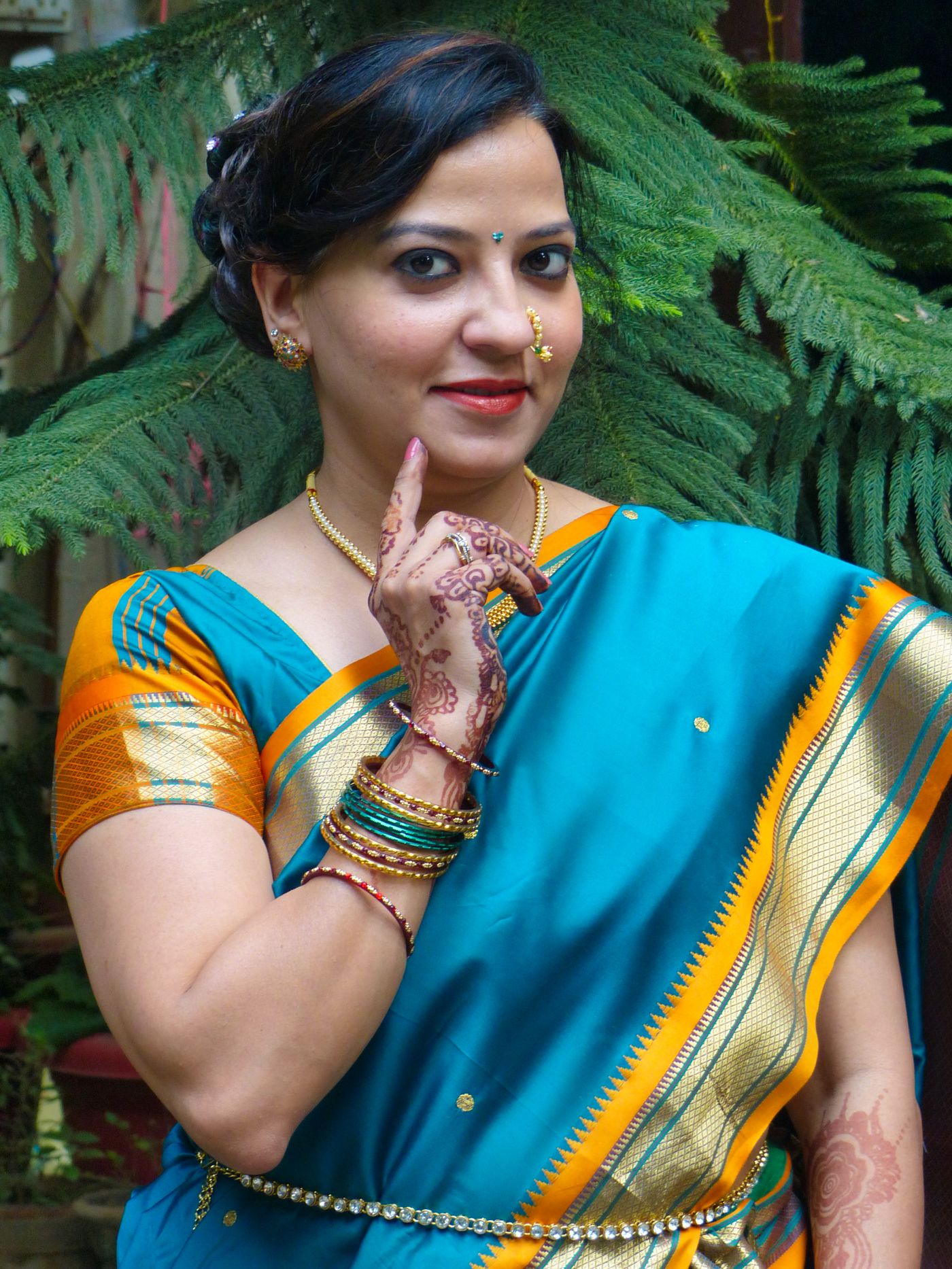 Woman wearing a blue saree with a bold yellow border and jewellery.