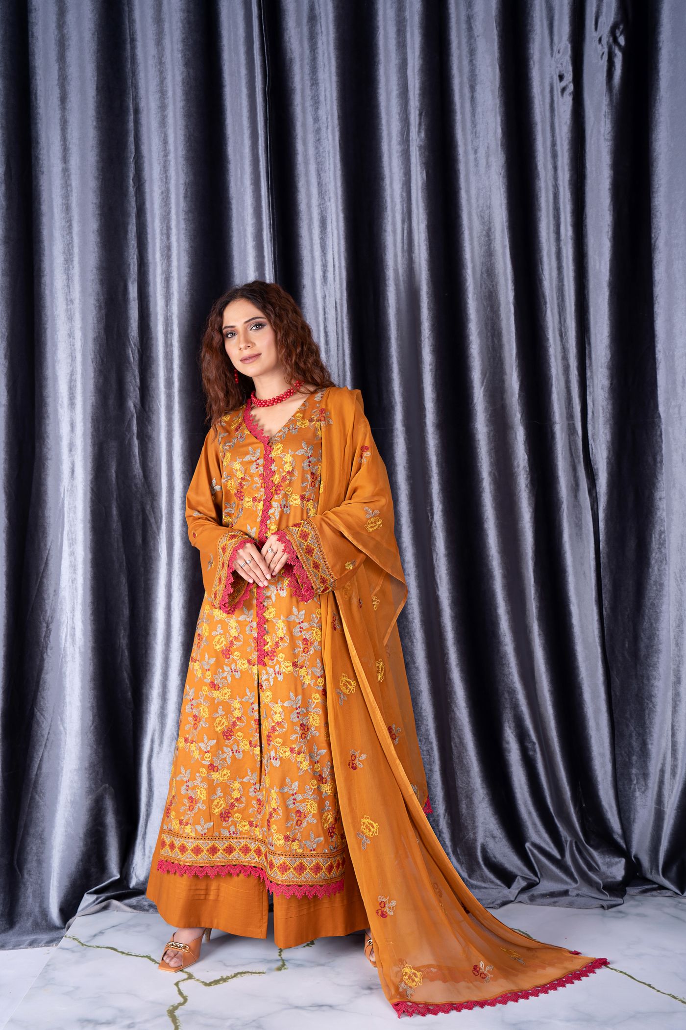 Woman wearing an orange embroidered kurta with few visible accessories.