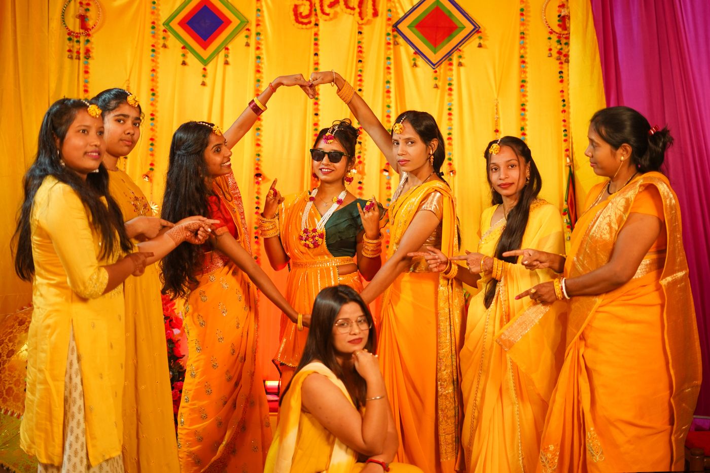 Women wearing yellow outfits together at a haldi celebration.