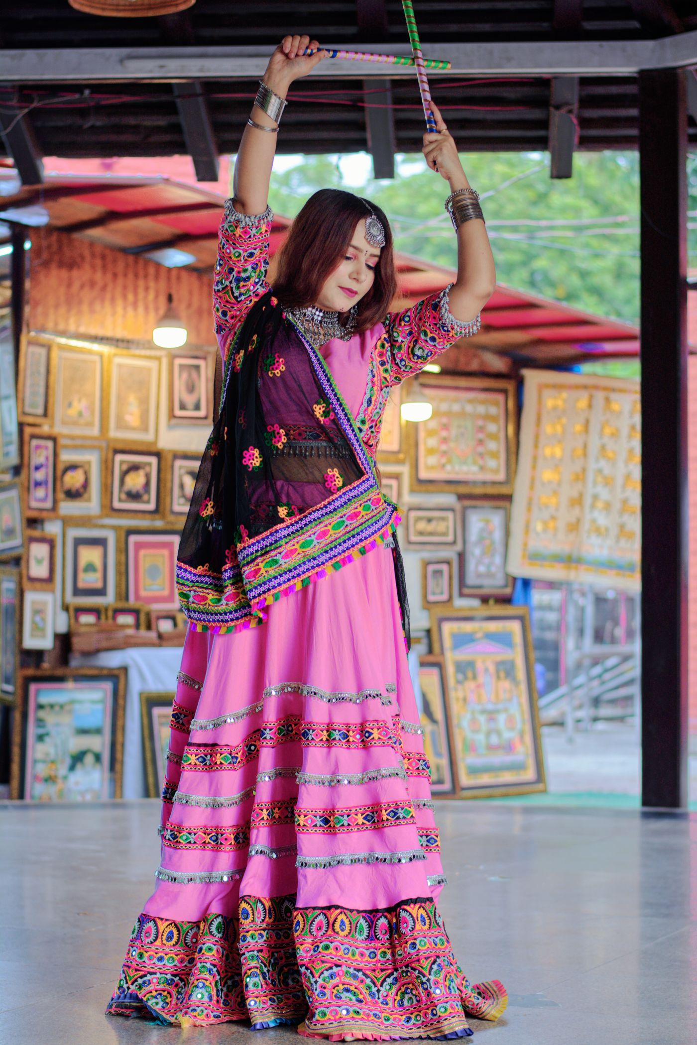 Woman dancing with raised arms in a colourful traditional skirt outfit.