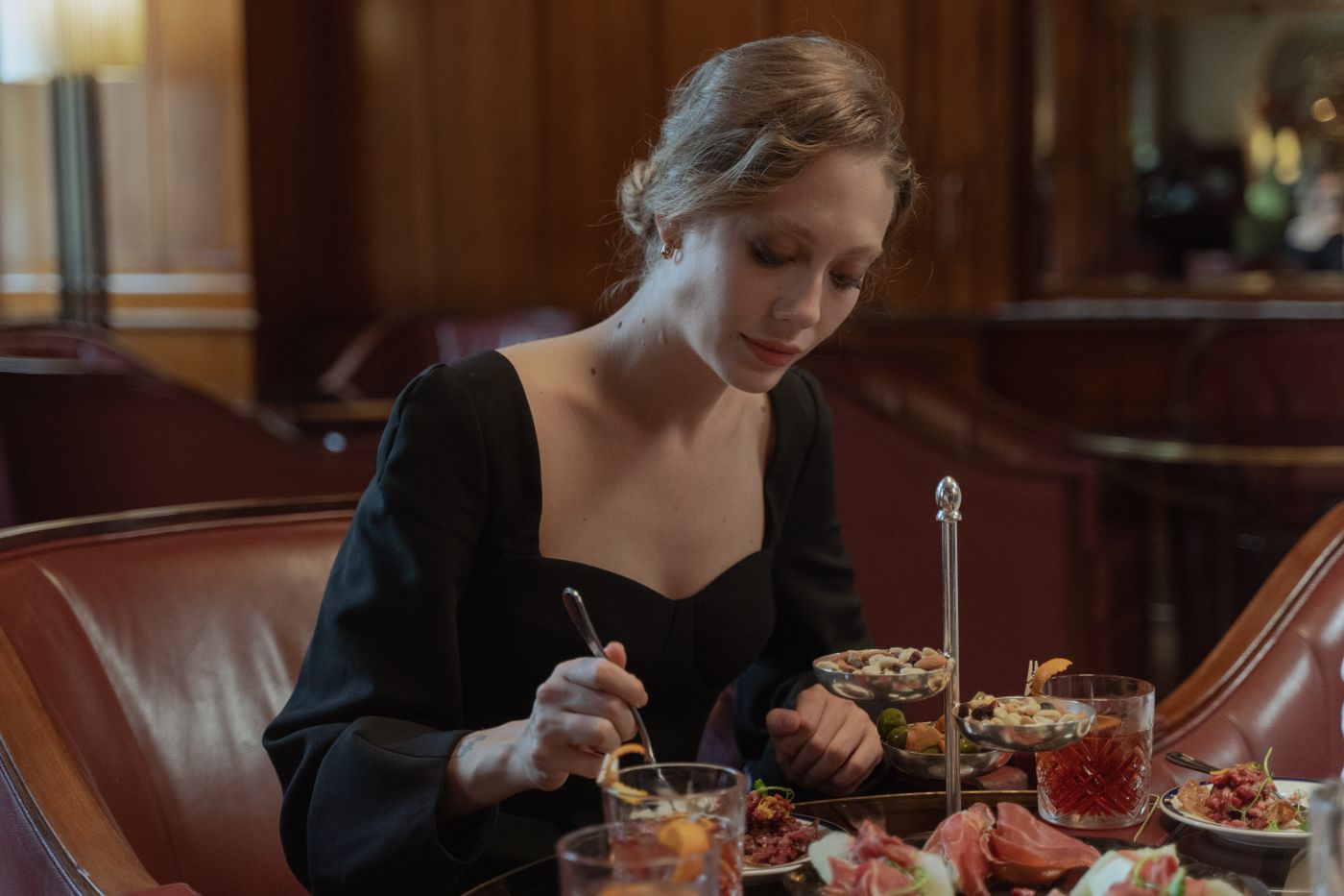Woman wearing a black dress while seated at a restaurant table.