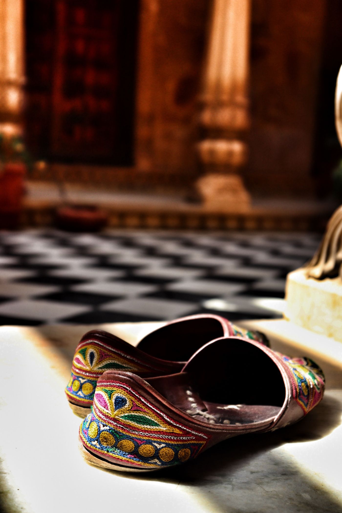 Pair of embroidered traditional juttis on a tabletop.