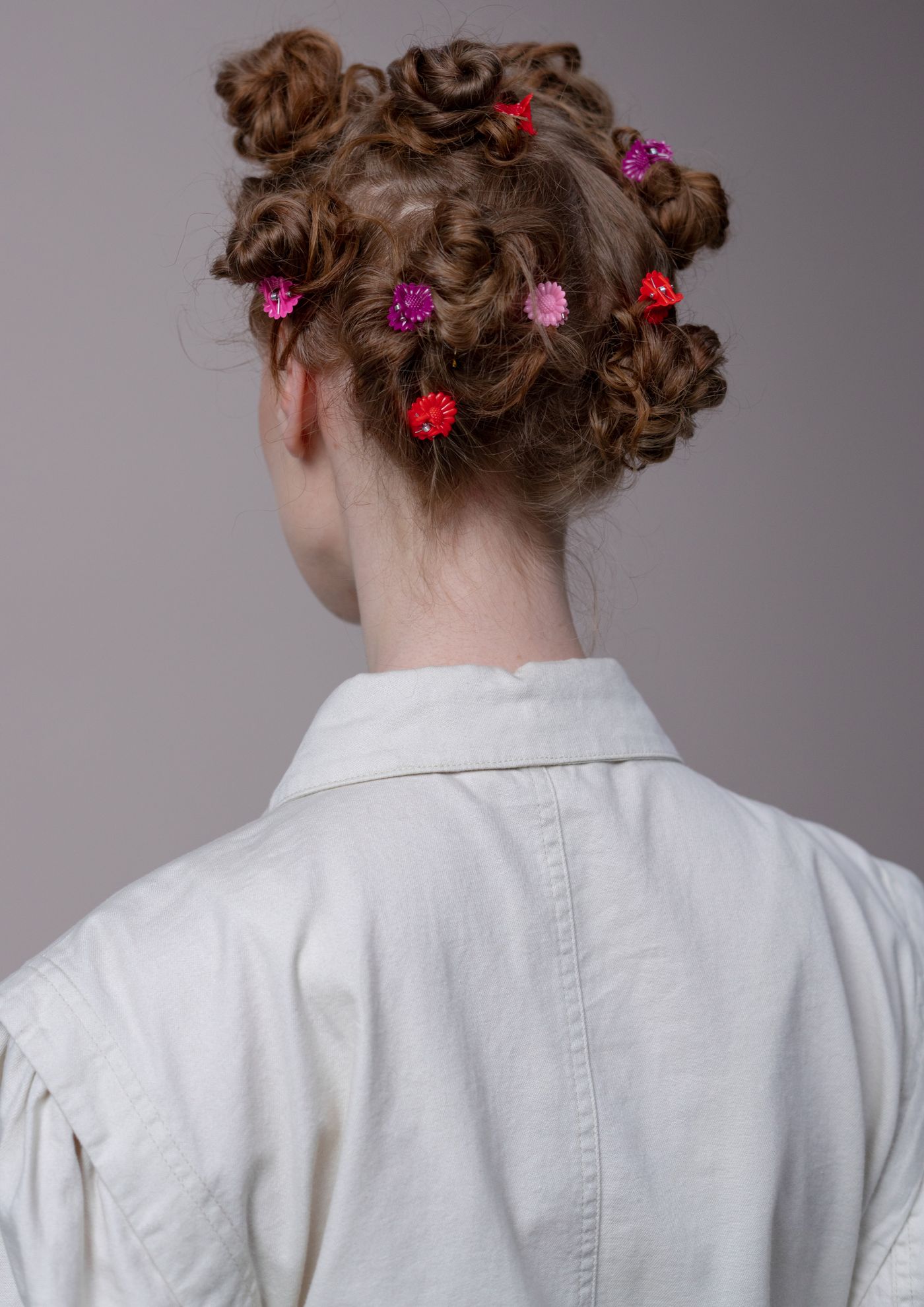 Back view of pinned-up hair with small colourful clips above a white collar.